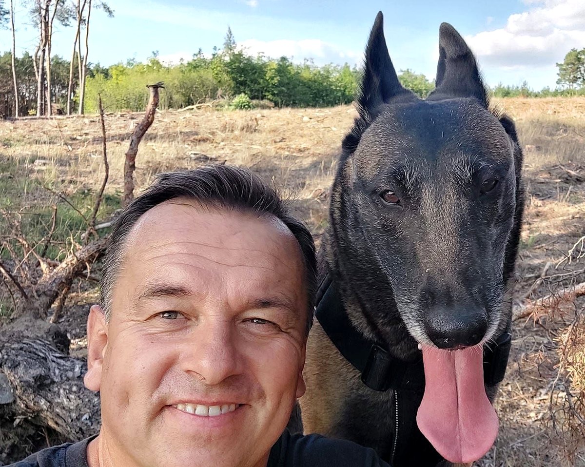 Hundetrainer Jarosław mit seinem Malinois im Wald.